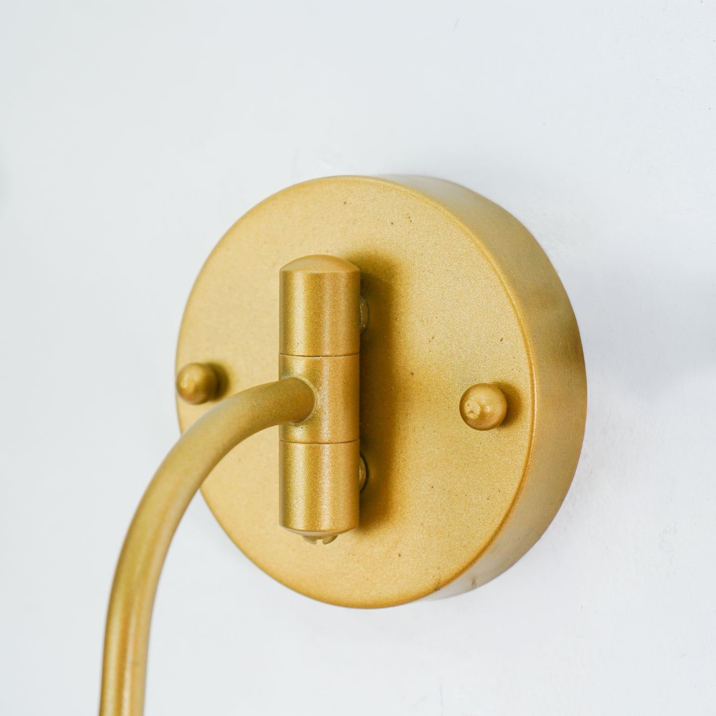 Closeup image of gooseneck brass swivel wall sconce with frosted glass shade for elegant modern home interior room decor.