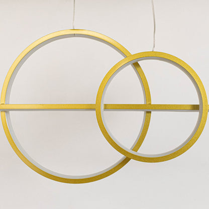 Closeup of gold pendant light with bright circular rings and dual cylindrical spotlights for stylish ceiling lighting.