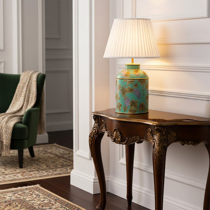 Green ceramic table lamp with pleated fabric shade styled on vintage wooden console table for elegant living room decor.
