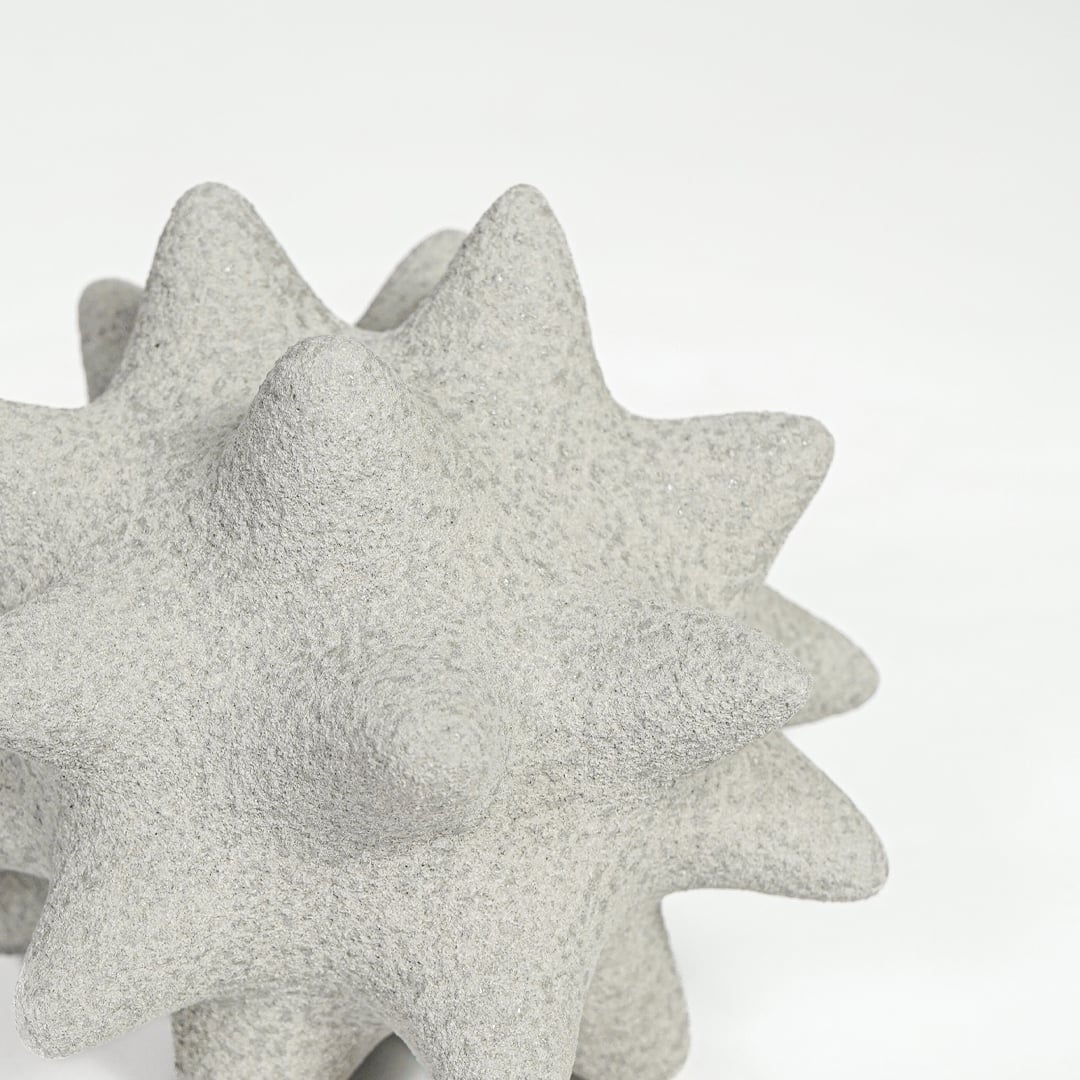 Close view of white ceramic star shaped decor featuring rough textured surface and sculpted pointed form.