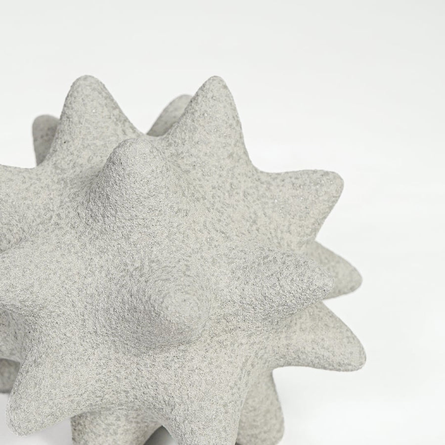 Close view of white ceramic star shaped decor featuring rough textured surface and sculpted pointed form.