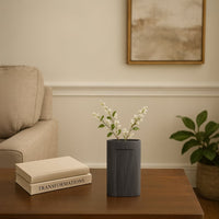 Dark grey textured ceramic vase with vertical ribbed pattern styled as modern table decor accent for contemporary living interiors.