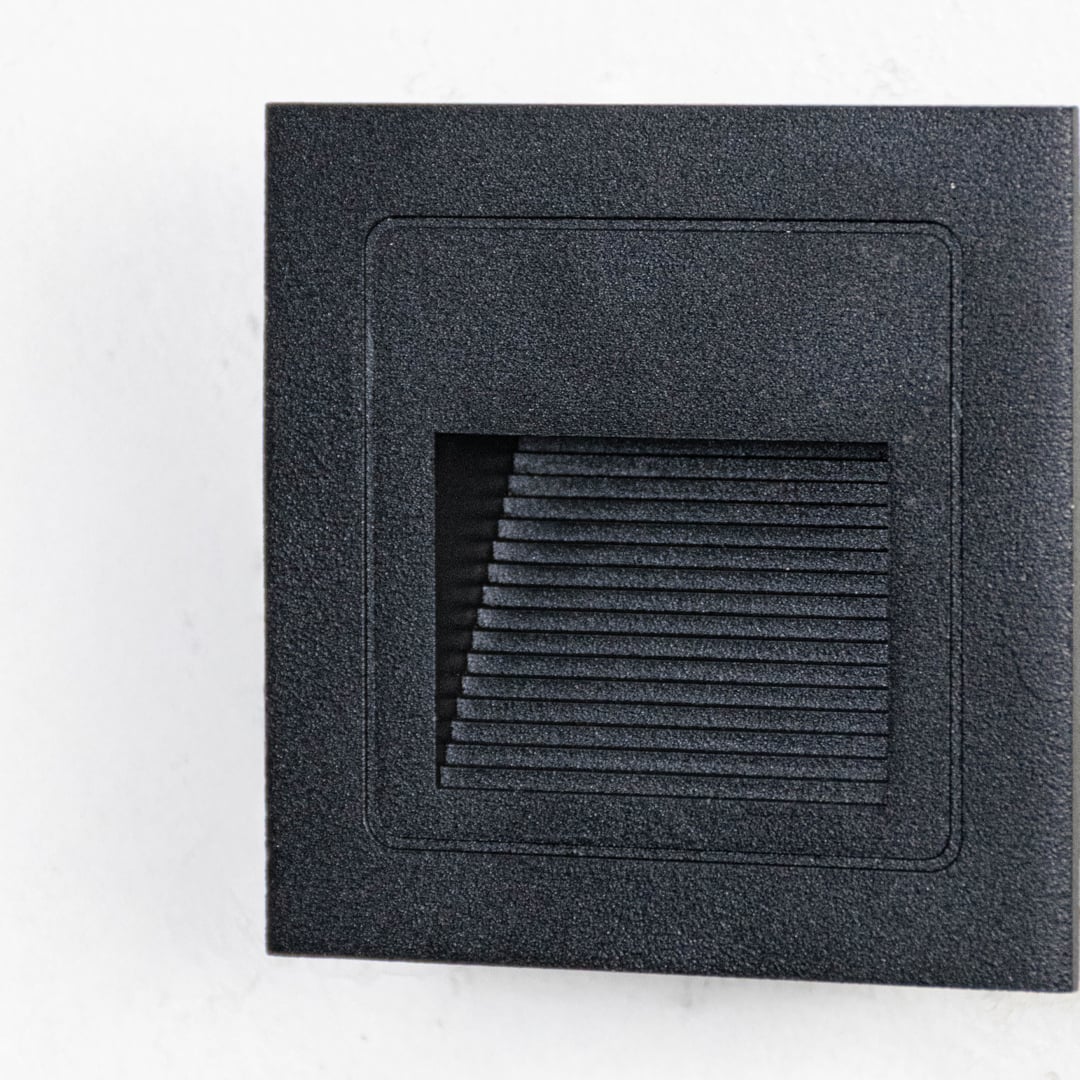Closeup of black outdoor wall lantern showing geometric frame frosted glass panel and clean contemporary exterior design.