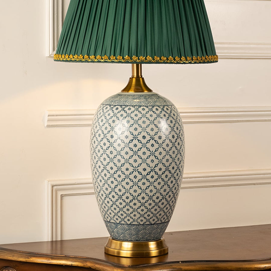 Closeup view of the patterned ceramic lamp base with gold detailing and rich green pleated lampshade showcasing texture and craftsmanship.