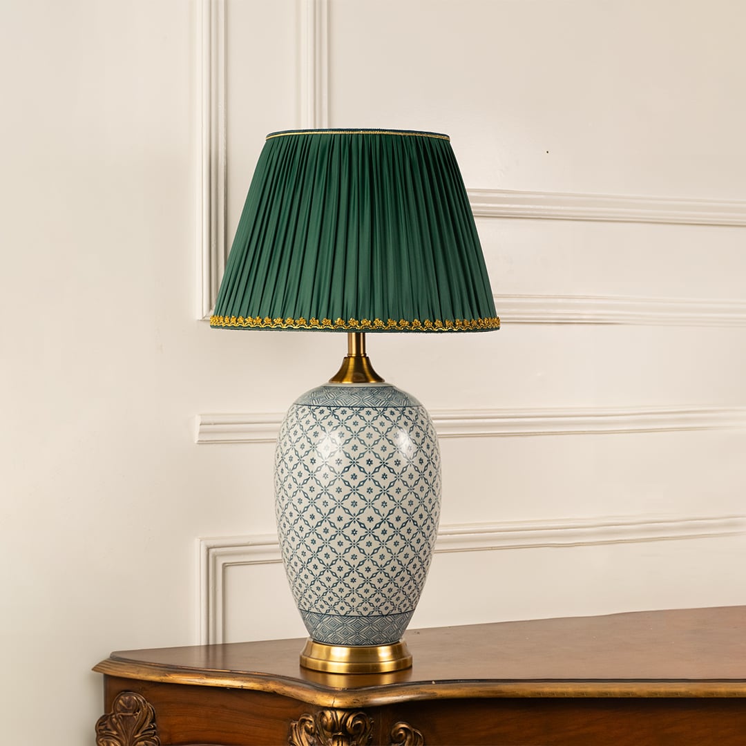 Classic ceramic table lamp with a green pleated shade and gold base displayed against a plain white background with no illumination.