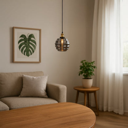Warm pendant light with rippled smoked glass shade glowing softly above a neutral sofa and wood table creating a cozy living room ambience with natural decor.