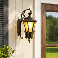 Vintage brass metal ornate scroll arm amber glass wall lantern on white vertical siding next to wood window porch lighting.