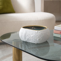 White textured ceramic bowl with gold rim placed on glass table for elegant modern home decor styling.