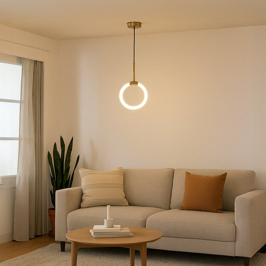 Modern gold pendant light glowing warmly above a cozy beige sofa in a minimalist living room interior decor.
