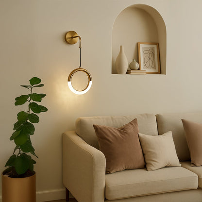 Elegant gold circular wall light glowing beside sofa creating warm and modern living room ambiance.