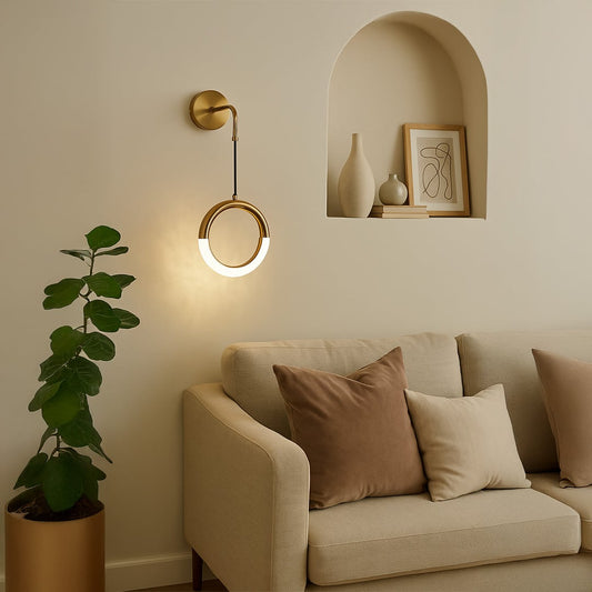 Elegant gold circular wall light glowing beside sofa creating warm and modern living room ambiance.