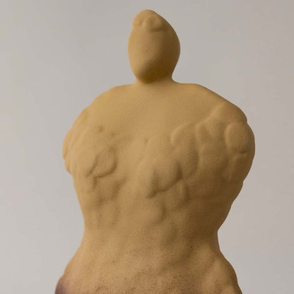 Hand sculpted yellow ceramic art piece closeup showing organic human form texture and raw matte finish for contemporary decor styling.