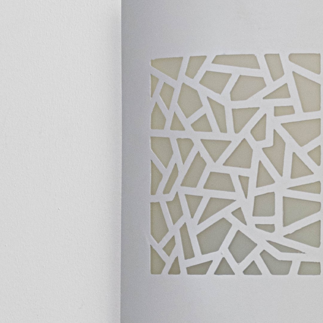 Closeup of decorative outdoor wall light panel featuring geometric cut pattern metal surface and modern architectural styling.
