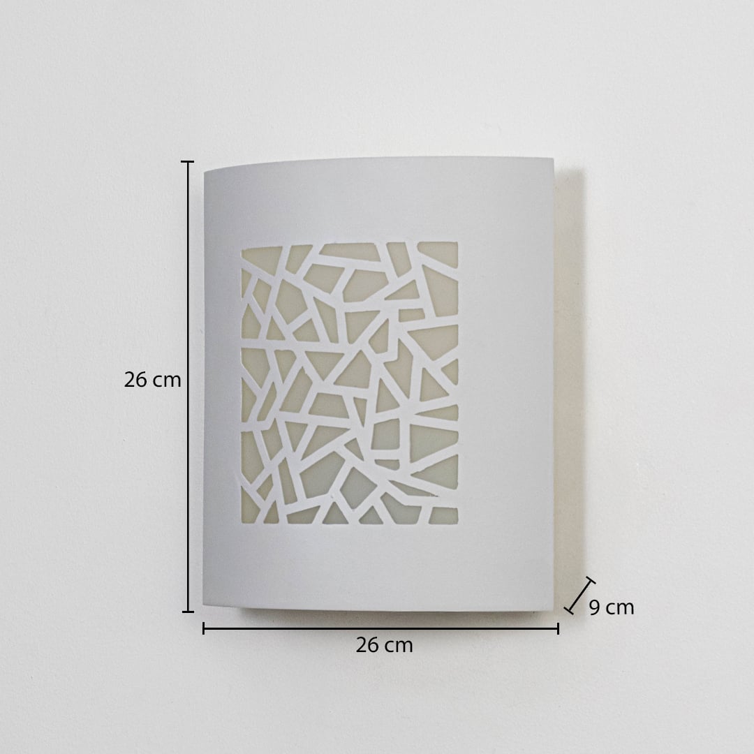 Modern outdoor wall light in white metal with geometric cut design mounted on wall showing 26 cm height 26 cm width and 9 cm depth.