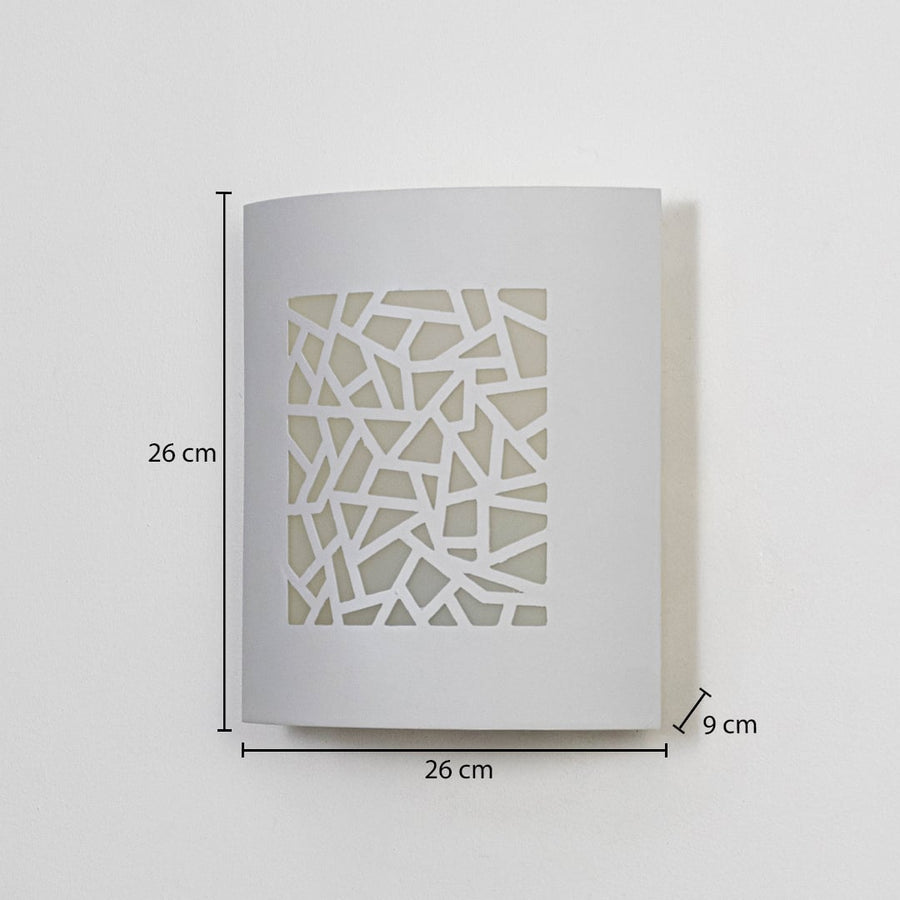 Modern outdoor wall light in white metal with geometric cut design mounted on wall showing 26 cm height 26 cm width and 9 cm depth.