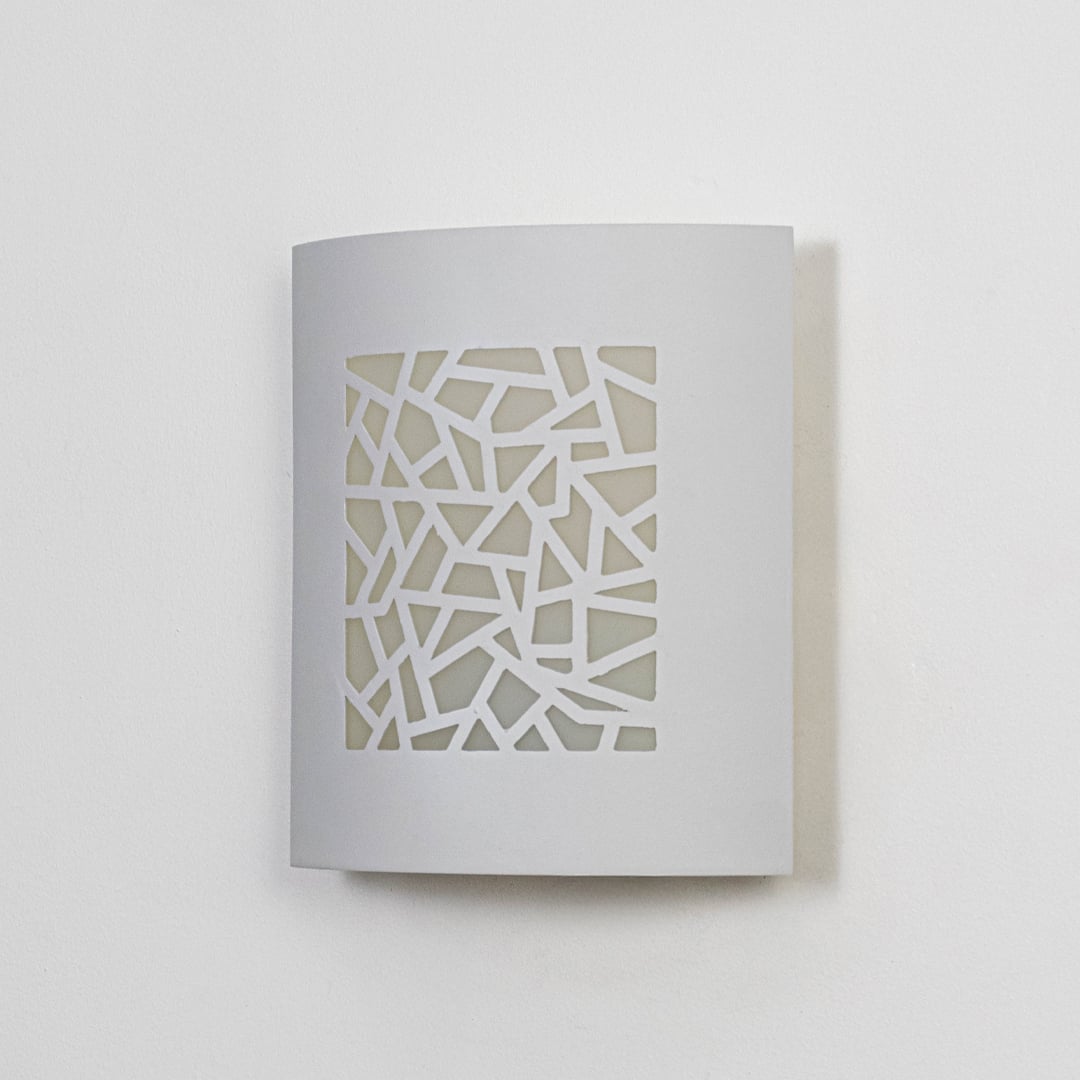 Minimal white ceramic wall light with geometric cutout front displayed off on clean white background.