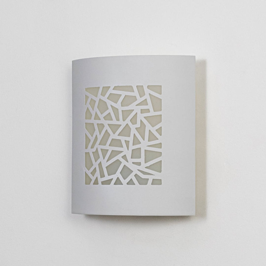 Minimal white ceramic wall light with geometric cutout front displayed off on clean white background.