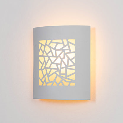 White metal wall light glowing warmly on white wall with geometric cutout design for modern decor.