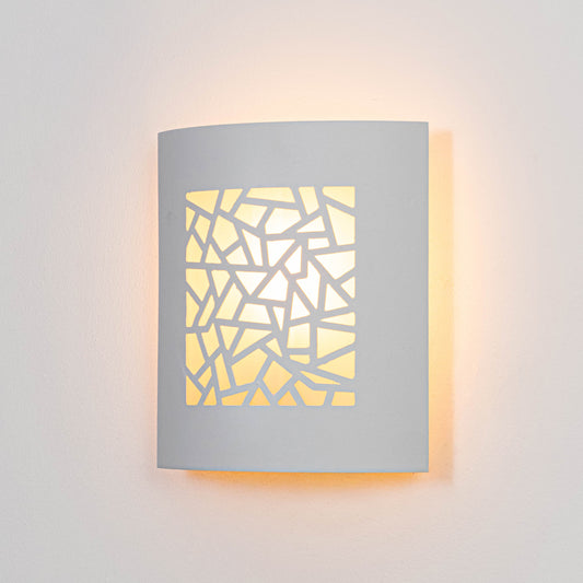 White metal wall light glowing warmly on white wall with geometric cutout design for modern decor.