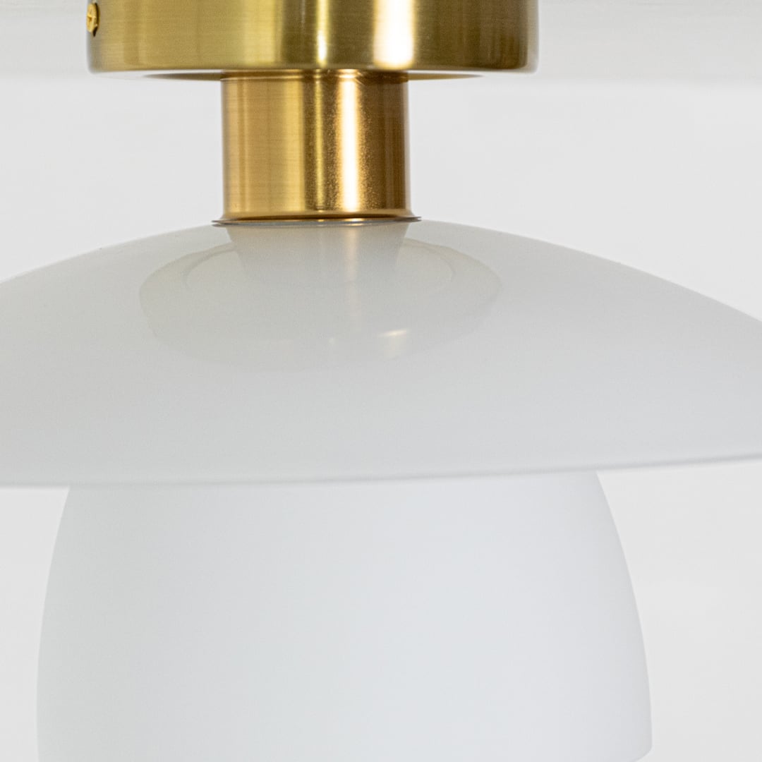Closeup of gold metal ceiling light highlighting the smooth white glass shade and polished gold mount designed for modern elegant home lighting.