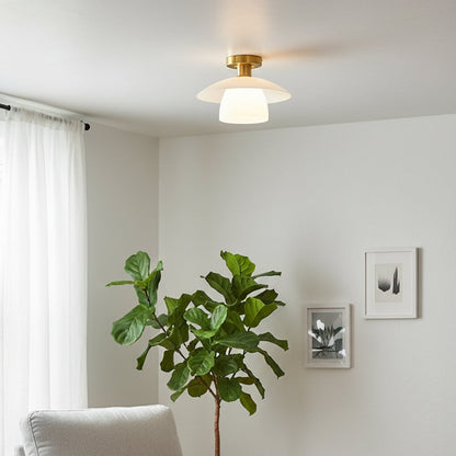 Gold metal ceiling light with white glass shade glowing softly in a modern living room creating a warm inviting and minimalist interior atmosphere.