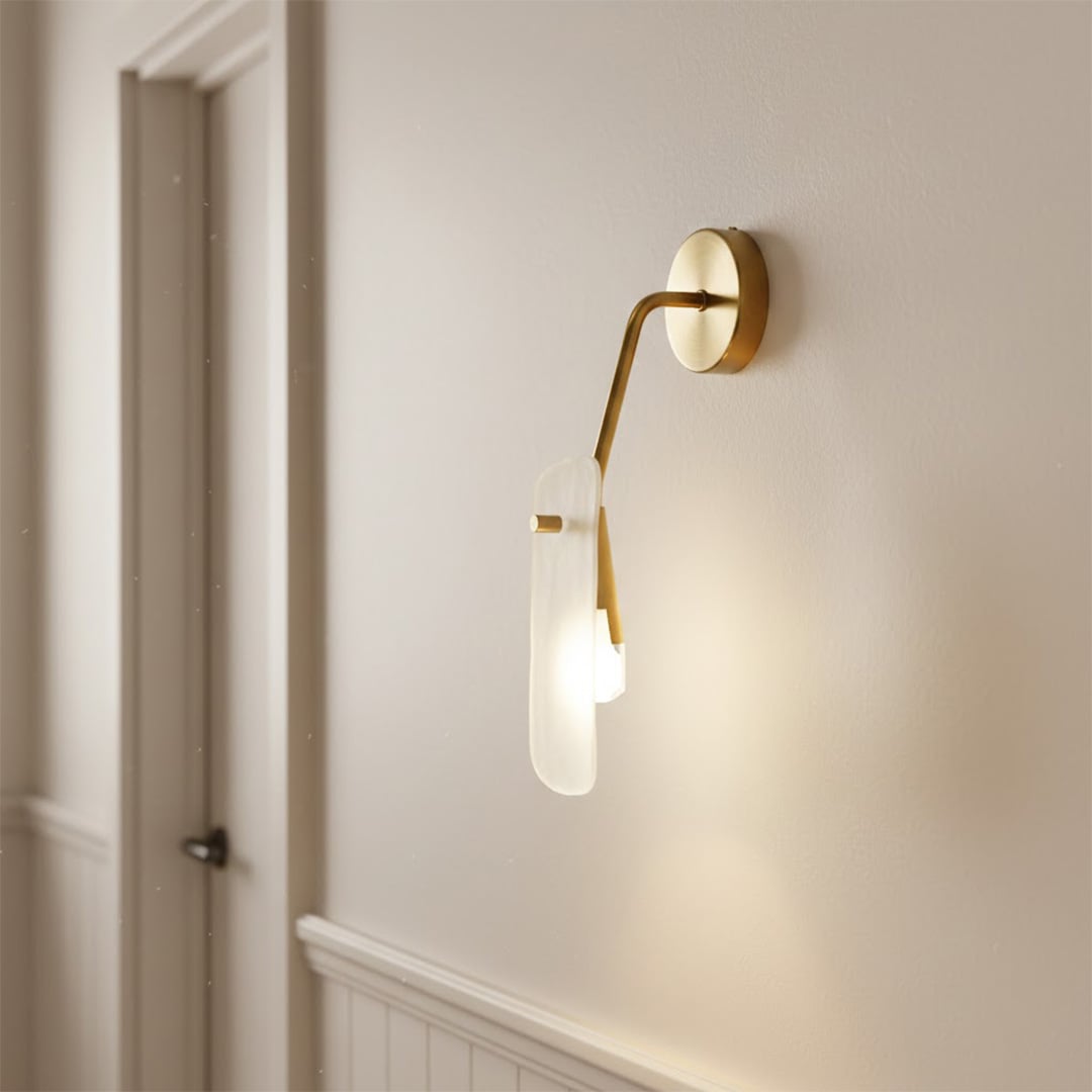 Luxury gold wall lamp with an artistic frosted glass panel diffuser illuminating a modern white hallway entry corner.