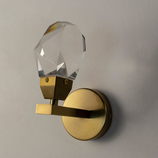 Modern crystal wall sconce with golden metal base displayed on white wall background for sophisticated interiors.