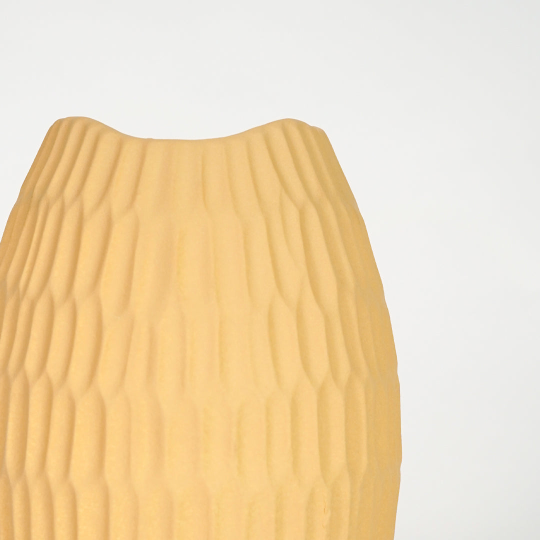 Closeup image of yellow ceramic textured vase for modern tabletop decor styling with elegant matte finish display.