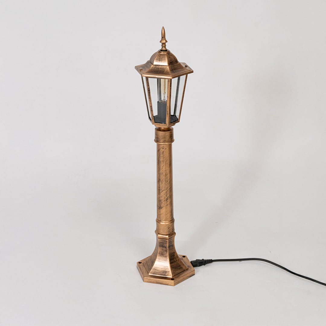 Antique gold pillar lamp post with clear glass body displayed off on white background for outdoor decor.