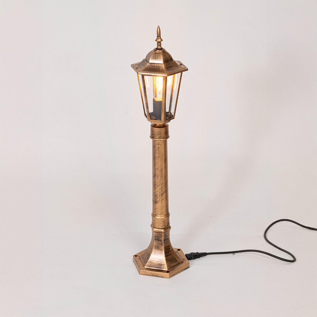 Antique gold outdoor garden light with warm glowing lantern panels for luxury exterior decor use.