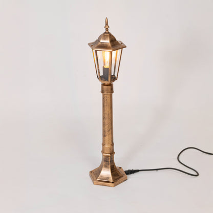 Antique gold outdoor garden light with warm glowing lantern panels for luxury exterior decor use.