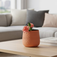 Terracotta textured metal vase with pink flowers on coffee table for warm modern living room home interior decor.