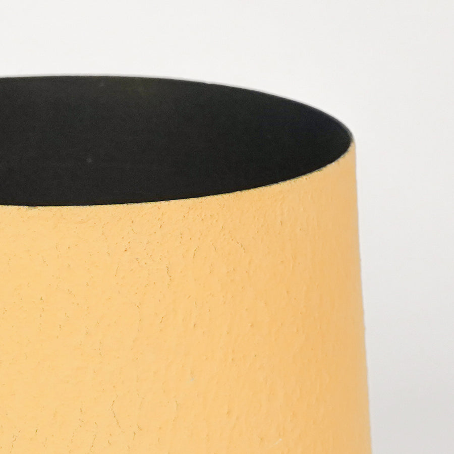 Detailed view of textured yellow matte metal surface on artisan vase for refined modern home decor and aesthetics.