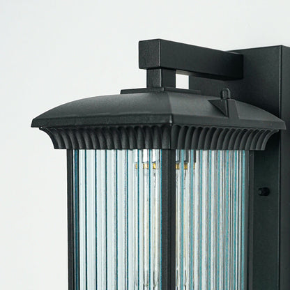 Close view of black metal outdoor wall light with ribbed glass shade showcasing durable weather resistant exterior lighting design.
