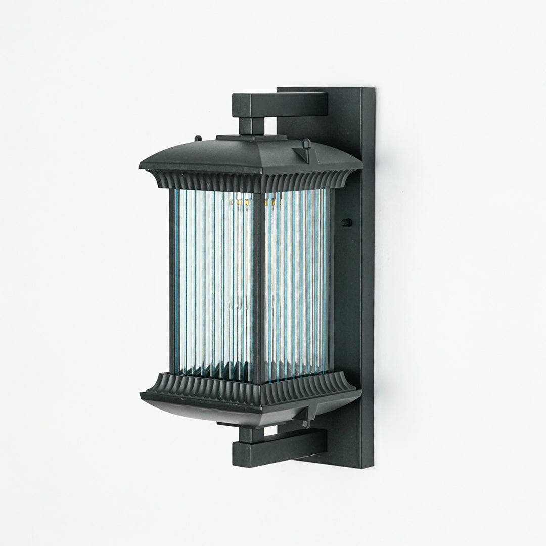 Minimal black outdoor wall light with vertical ribbed glass shade on neutral wall background ideal for garden or patio lighting.