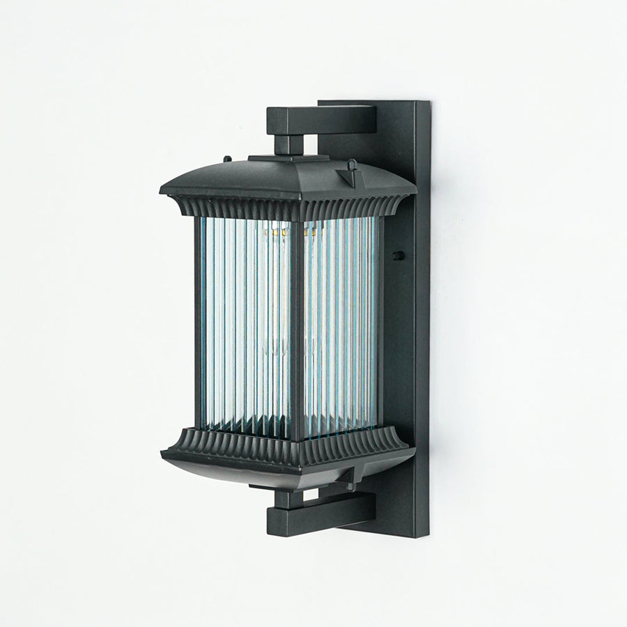 Minimal black outdoor wall light with vertical ribbed glass shade on neutral wall background ideal for garden or patio lighting.