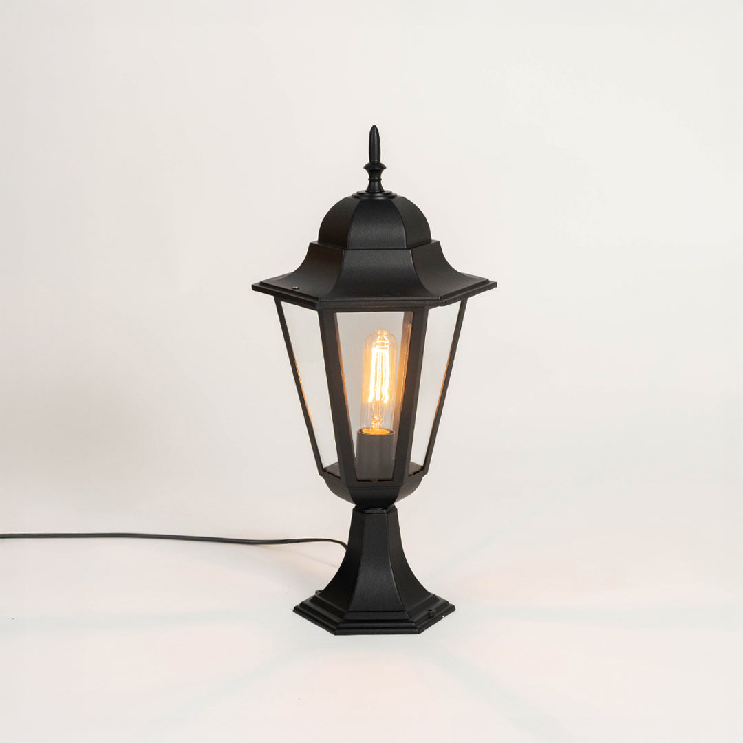 Modern black outdoor gate light with glowing bulb and glass shade for stylish exterior decor use.