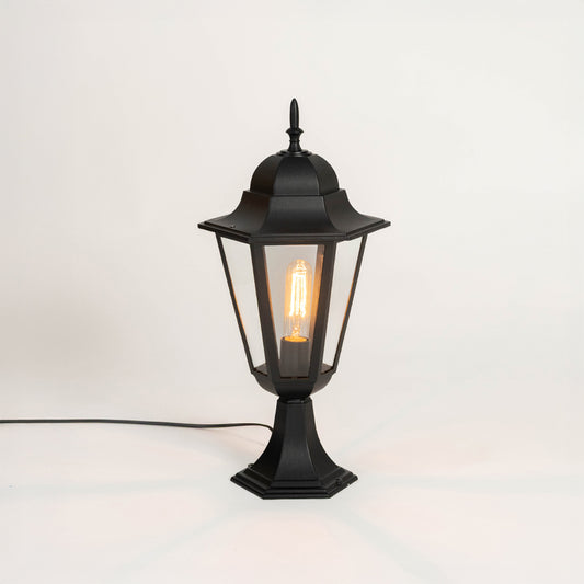 Modern black outdoor gate light with glowing bulb and glass shade for stylish exterior decor use.