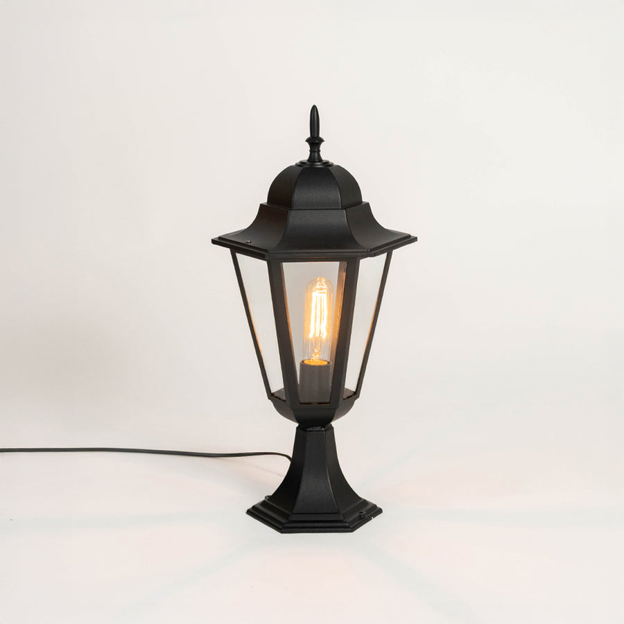 Modern black outdoor gate light with glowing bulb and glass shade for stylish exterior decor use.