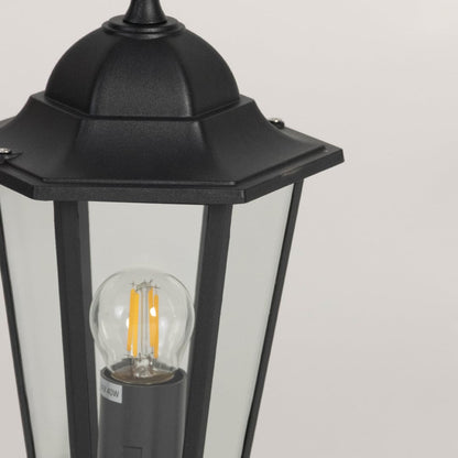 Closeup of black pillar lamp with clear glass and bulb highlighting elegant details for outdoor gate and garden lighting style.