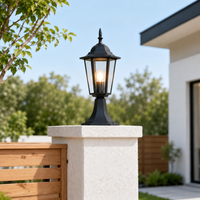 Traditional black aluminum tapered cage glass pillar post lantern light on concrete pillar post next to wooden fence yard.