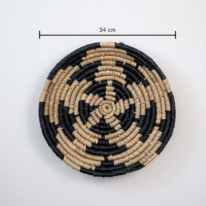 Handwoven seagrass round wall basket decor in natural beige and black with geometric woven pattern and size guide on white.