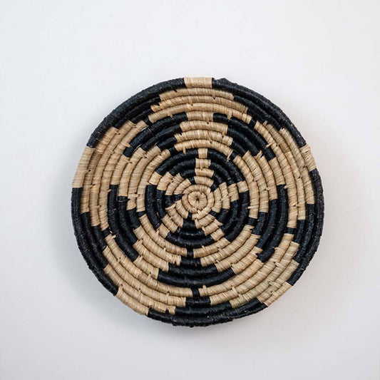 Handwoven seagrass round wall basket decor in natural beige and black with geometric woven pattern displayed on white background.