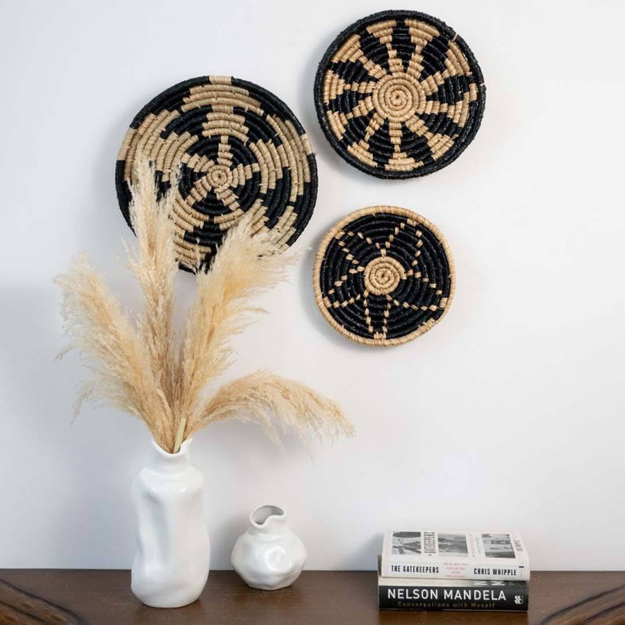 Handwoven seagrass wall basket decor set in natural beige and black adding artisan boho charm to living room walls.