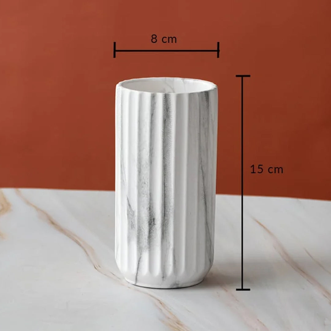 A white ribbed ceramic cup with gray marble veining, shown on a marble surface against a terracotta background, with black dimension lines indicating 8 cm width and 15 cm height.