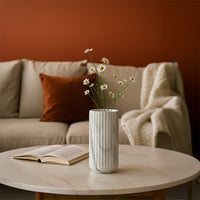 A marble textured cylindrical vase styled against a warm terracotta backdrop creating a modern refined look with soft grey veining details.