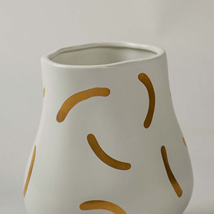 A closeup view of a curved ceramic vase featuring organic golden stroke detailing highlighting its artistic texture and smooth matte finish for decor styling.