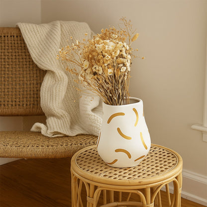 A stylish ceramic vase with a soft curved form and warm golden strokes displayed in a minimal lifestyle setting creating a calm and modern decorative look.