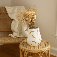 A stylish ceramic vase with a soft curved form and warm golden strokes displayed in a minimal lifestyle setting creating a calm and modern decorative look.
