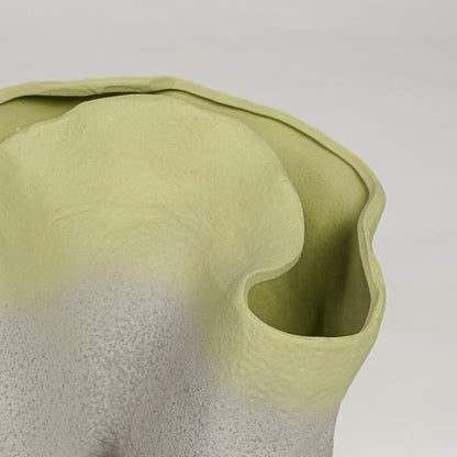 Close up view of green ceramic sculpted vase highlighting organic curved edges and textured matte finish.